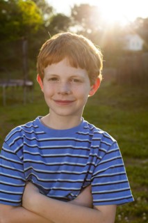 Smiling Caucasian boy standing in sunny backyard