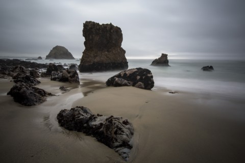 Rock formations and ocean waves on sandy beach
