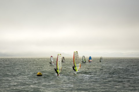 Windsurfers on ocean under cloudy sky