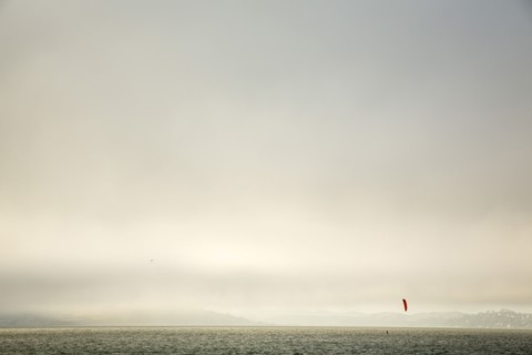 Kiteboarder on ocean under cloudy sky