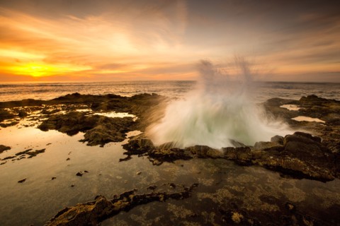 Ocean waves crashing in Thor's Well at sunset
