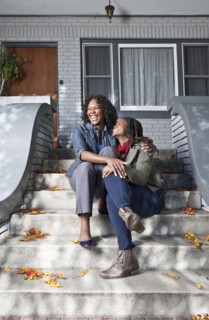 Black mother and daughter sitting on front stoop