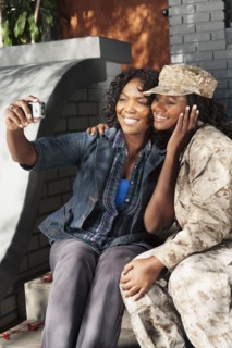 Black mother taking self-portrait with soldier daughter