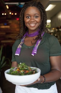 Black waitress serving salad in restaurant