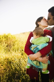 Mother holding baby and kissing husband