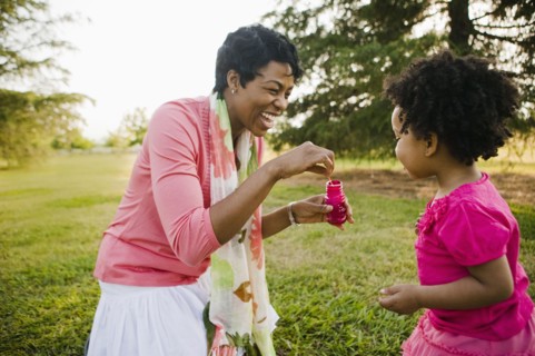 Black mother and daughter blowing bubbles in park