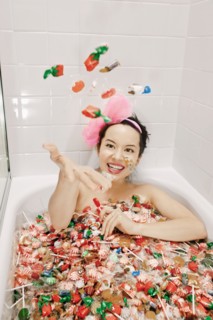 Mixed race woman taking a bath in candy