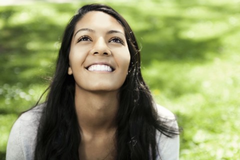 Smiling Hispanic teenager sitting in grass