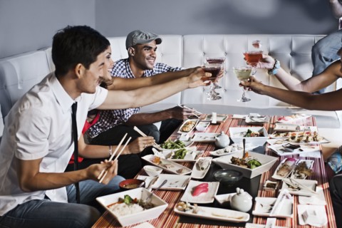 Friends toasting and eating together in restaurant