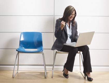 Hispanic businesswoman using laptop in waiting room