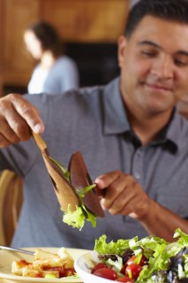 Mixed race man serving himself salad