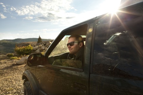 Man sitting in car overlooking rural landscape