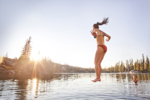 Woman jumping into rural lake