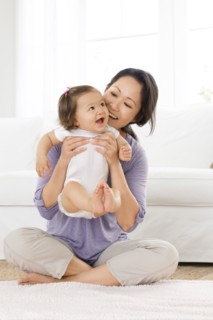 Mother playing with baby girl in living room