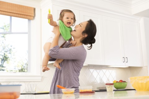Mother holding baby girl in kitchen