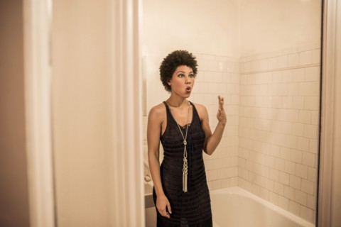 Woman making a face in bathroom mirror