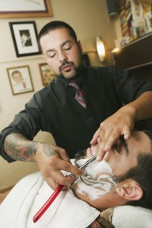 Hispanic barber shaving man's face