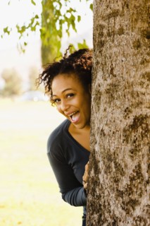 Playful African woman behind tree