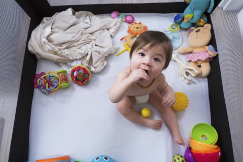 Mixed race baby girl sitting in playpen