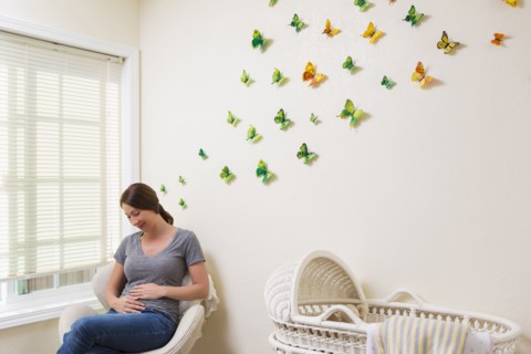Mixed race pregnant woman sitting in nursery