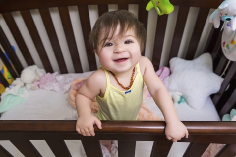 Mixed race baby girl standing in crib