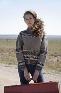 Mixed race woman standing on dirt road with suitcase