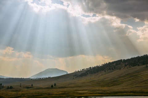 Sunbeams shining through clouds over rolling rural landscape