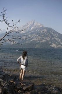 Caucasian woman standing in Jenny Lake admiring Great Teton mountains