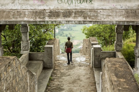 Man walking under stone walkway