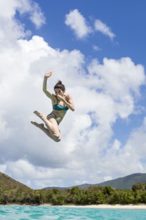 Caucasian woman jumping into tropical ocean