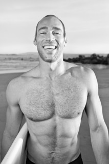 Mixed race man carrying surfboard on beach