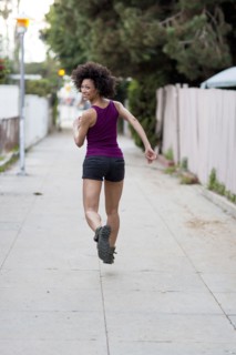 Smiling Mixed Race woman running on sidewalk