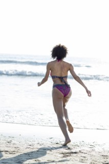 Mixed Race woman wearing bikini running to ocean