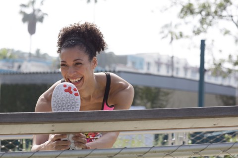 Mixed Race woman stretching leg on banister