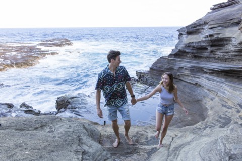 Smiling couple walking on rock formations at beach