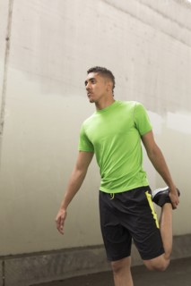 Mixed Race man stretching leg near wall