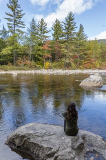 Caucasian woman sitting on rock relaxing near river