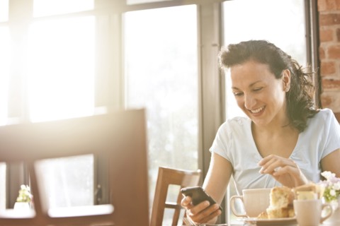 Hispanic woman in cafe using cell phone