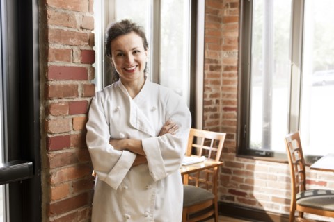 Hispanic chef leaning against wall in cafe
