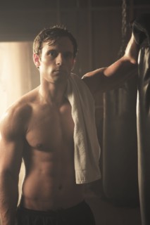 Fatigued boxer leaning on punching bag