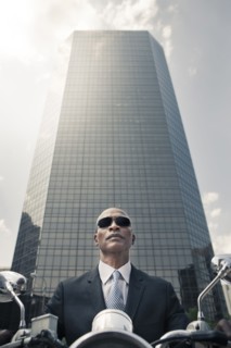 Black businessman riding motorcycle in city