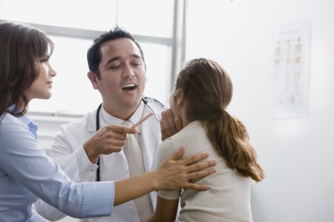 Doctor examining patient while mother watches