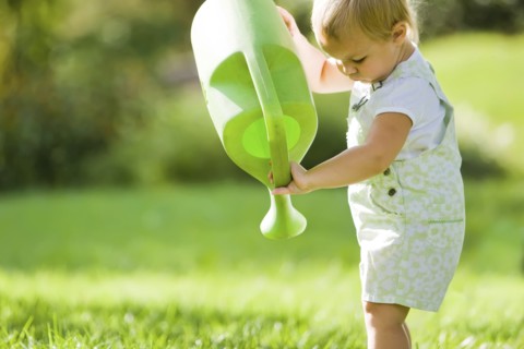 Caucasian baby lifting watering can