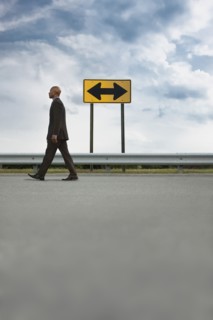 African American businessman walking on road near road sign