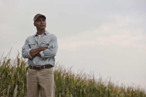 African American man standing in field with arms crossed