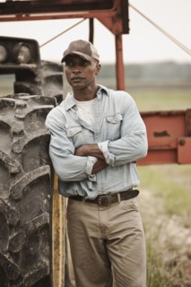 African American farmer standing near tractor
