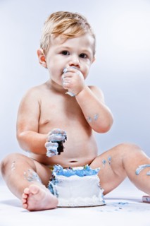 Caucasian baby eating birthday cake