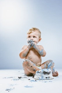 Caucasian baby eating birthday cake