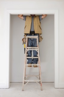 Caucasian carpenter standing on ladder in doorway