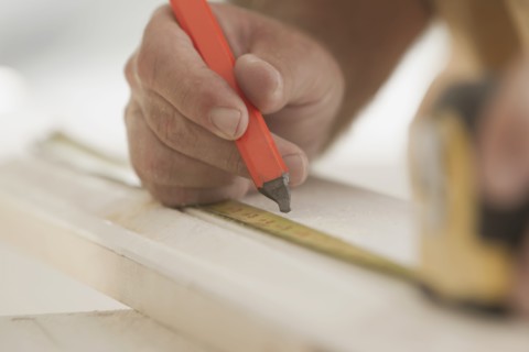 Caucasian carpenter measuring lumber